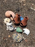 Overview of all outdoor art pieces arranged on gravel ground, showing terracotta lanterns, ceramic animal figurines, and stone turtle sculpture.