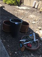 All items grouped together outdoors on gravel, showing planters and wind chime parts.