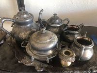 Wide shot of the entire 15-piece silver plated tea set on the ornate serving tray showing teapot, sugar bowl, creamer, butter dish, candle holder, and tray.