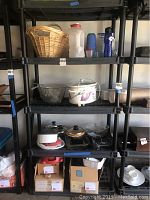 Black plastic shelving unit with various kitchenware items placed on shelves (not included).