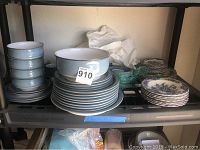 Shelf with stacked blue stoneware plates, bowls, cups, and additional plates with blue floral pattern.
