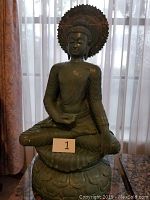Full front view of seated green Buddha statue on lotus base