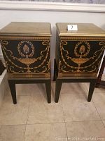 Two matching black and gold painted wooden box tables standing side by side.