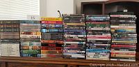 Large assortment of DVDs stacked on table with titles including Lost, The Sopranos, Fringe, Monk, The Simpsons and others.
