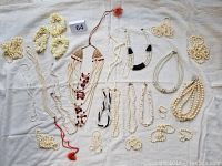 Top view of entire collection showcasing various pearl style necklaces, bracelets, and earrings laid out on a light fabric background.