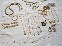 Full overview of the jewelry lot showing various necklaces, bangles, earrings, and pins arranged on a white fabric.