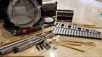 Full lot of percussion instruments including xylophone, snare drum with case, electric Tambura, mallets, and music stands on floor.
