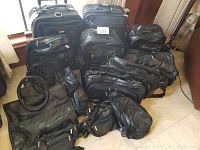 Photo showing the full lot of black luggage items including suitcases, handbags, and waist bags arranged on the floor