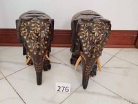 Front view of both elephant figurines showing decorative gold-painted floral designs on faces and trunks