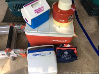 Lot items including Coleman 34 qt cooler, Igloo Minimate Deluxe cooler, Coleman 8 qt personal cooler, Thermos jug, and a soft insulated lunch bag.