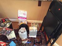Three small heaters and one small fan with various household items around them