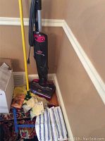Bissell Steam & Sweep Pet cleaner with yellow-handled dust mop and striped extra mop pads on floor beside it.