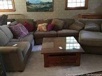 Overall view of three-piece sectional arranged around coffee table, showing chaise on right, sofa on left, and loveseat in center with accent pillows.