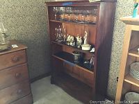 Full view of antique wooden bookcase with glassware and figurines on shelves showing size and shape