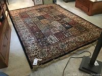 Rectangular area rug laid flat on floor showing patchwork varied pattern and wide decorative border.