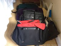Photo showing multiple bags including a black leatherette laptop bag, a red and black bag, and fabric basket, with two dryer vent brushes in background.