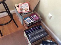 Three cardboard boxes containing books: two boxes of dermatology medical textbooks and one box with mixed books including a home improvement book visible