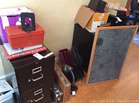 Overall view of the office supplies including red plastic box, filing drawers, chalkboard, gooseneck lamp, and file folders.