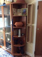 Photo showing corner shelf unit with terra cotta bake dish, pewter stein, creamers, and other decor items.