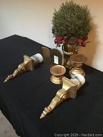 Photo showing collection of gold leaf accessories including plant centerpiece, candle holders, wall brackets, and picture frame