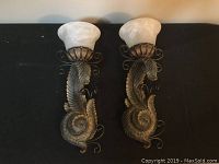 Front view of the two wall sconces showing leaf design and white alabaster-style shades