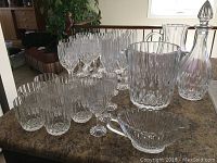 Photo shows the full lot of 29 pieces crystal glassware set including glasses, pitcher, decanter, and bowl.