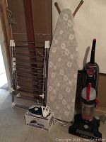 Photo showing all items including vacuum, ironing board, iron on box, and clothes rack together.