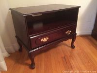 Front-side view showing drawer with ornate handles, open shelf, and curved Queen Anne style legs.