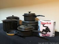 Full set of pots, pans, and boxed Starfrit food chopper from side-angle view.