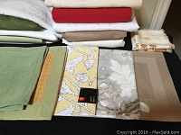 Close-up image of beige, yellow floral, and gray floral linens plus green placemats or runners.