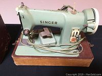 Side view of the vintage Singer sewing machine showing the foot pedal and machine details.
