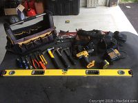 Full lot on table including tool bag, tool belts, level, screwdrivers, hammers, drill and accessories