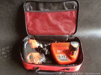 Milwaukee M12 cordless palm nailer, battery, and charger inside red carrying case