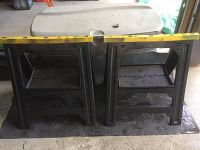 Pair of black Stanley plastic work horses side by side on a floor, with measuring tape showing approximately 25 inches wide