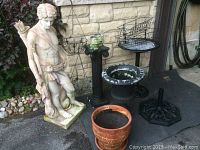 Overall grouping of statue, planters, hanging baskets and pedestals on driveway