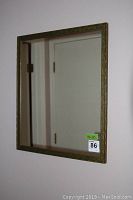 Wall mirror with decorative antique gold-tone frame reflecting door and hallway
