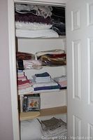 Photo of closet showing shelving with folded towels, sheets, blankets, and pillows arranged in stacks.