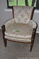 Front view of a wooden armchair with floral upholstery and removable cushion showing overall condition and design.
