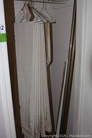 Beige curtain folded and hung on a wire hanger, showing fabric texture and color