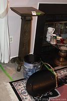 Solid wood pedestal stand next to fireplace with decorative tin and wood holder in front