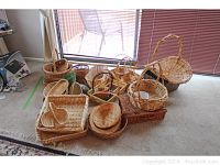 Group photo of a large pile of woven baskets of various shapes, sizes, and colors including round and rectangular baskets visible through window light.
