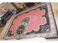 Full view of the large wool area rug with pink background and ornate border design.