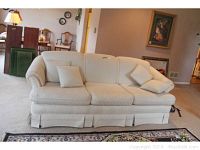 Full view of cream white upholstered sofa with three seat cushions and matching accent pillows, showing overall shape and condition.