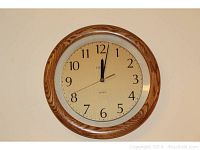 Round quartz wall clock with wood and metal frame, showing clock face in detail.