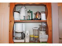 Wide shelf view showing multiple kitchen appliances including coffee makers, blender, food processor, and glass jars