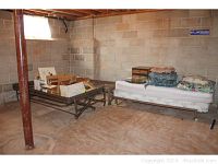 Basement photo showing two metal trundle bed frames side by side with various items on and around them.