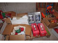 Wide view of multiple cardboard boxes containing hurricane lamps, boxed candle holders, and other items wrapped in packing paper.