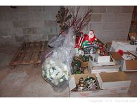 Overview photo showing the full assortment of Christmas decorations stored in boxes and plastic bags on a basement floor.