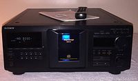 Front view of the Sony CDP CX400 Compact Disc Player showing LED display, control buttons, disc carousel closed, remote and manual on top.