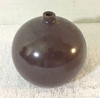 Full side view showing the round brown glazed pottery vase with narrow opening at the top.